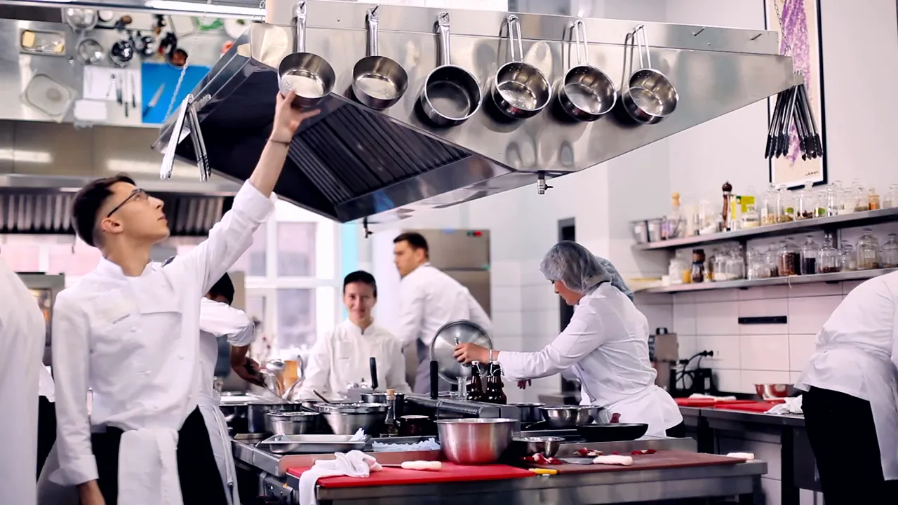 Equipe de cozinheiros trabalhando em uma cozinha profissional de inox.